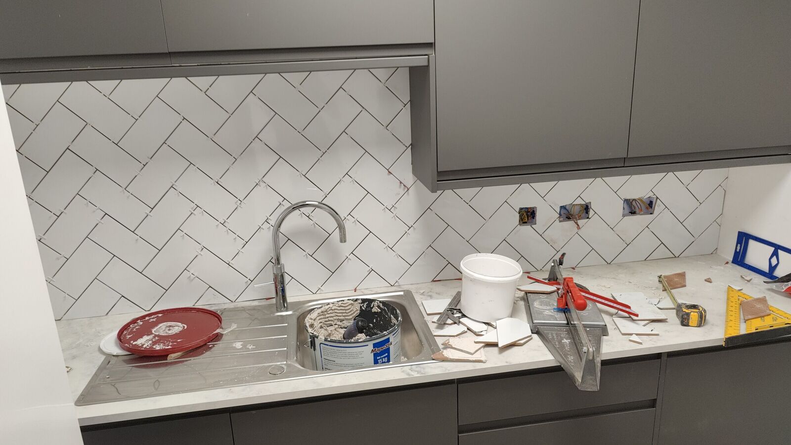 Herringbone white tiled splashback and grey handleless kitchen units